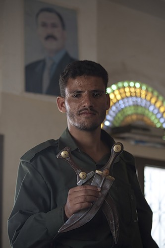 Солдат из города Заидия с кинжалами на фоне фотографии Али Абдаллы Салеха. Фото Анны Баскаковой