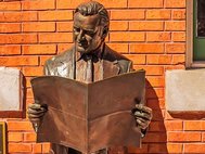 Бронзовый памятник–мужчина читает газету