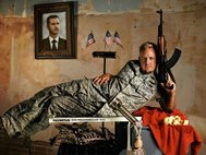 Американский солдат позирующий на фоне с портретом Б. Асада