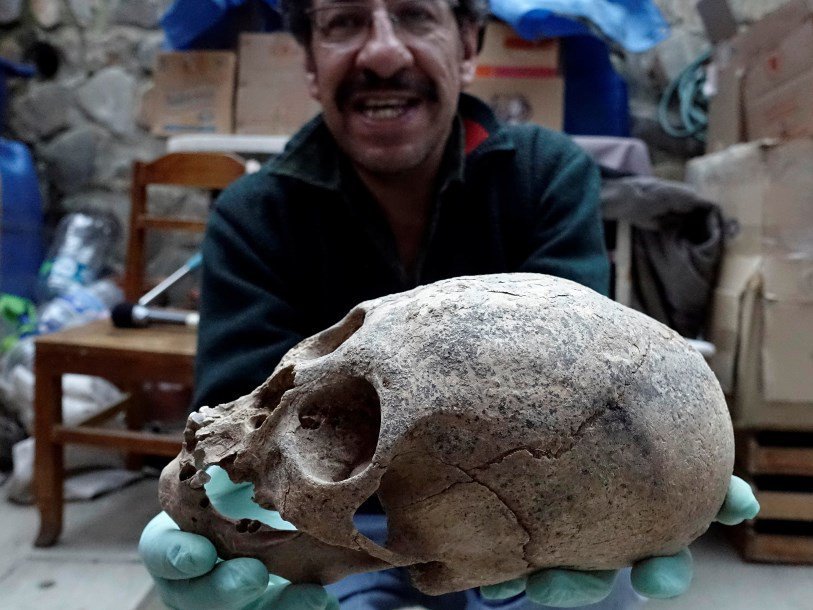 Один из археологов с найденным в захоронении черепом